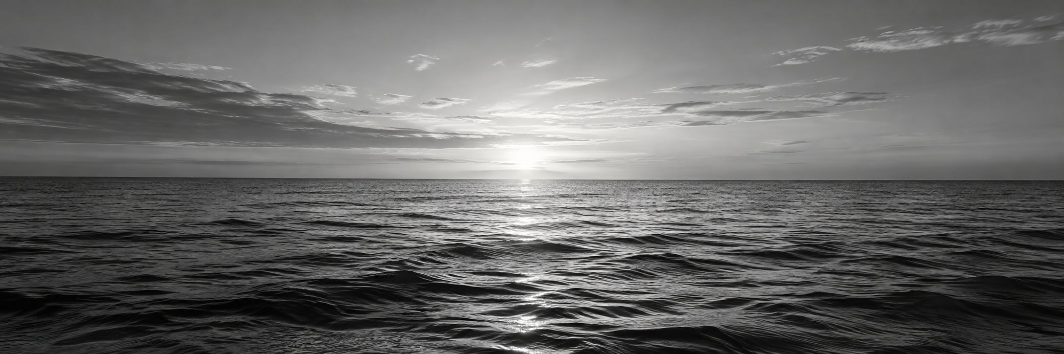 La mer calme à l’aube, avec le soleil au centre de l’horizon.